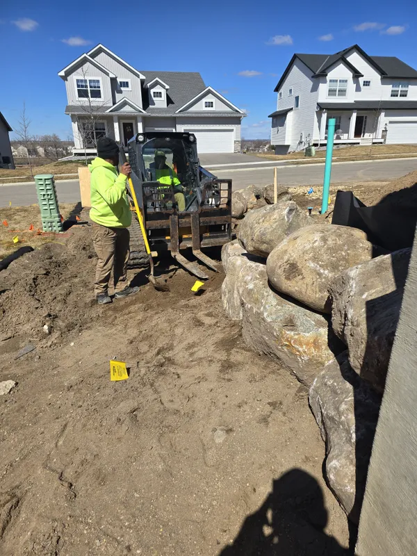 Ristau crew operating mini excavator for boulder placement at new construction
