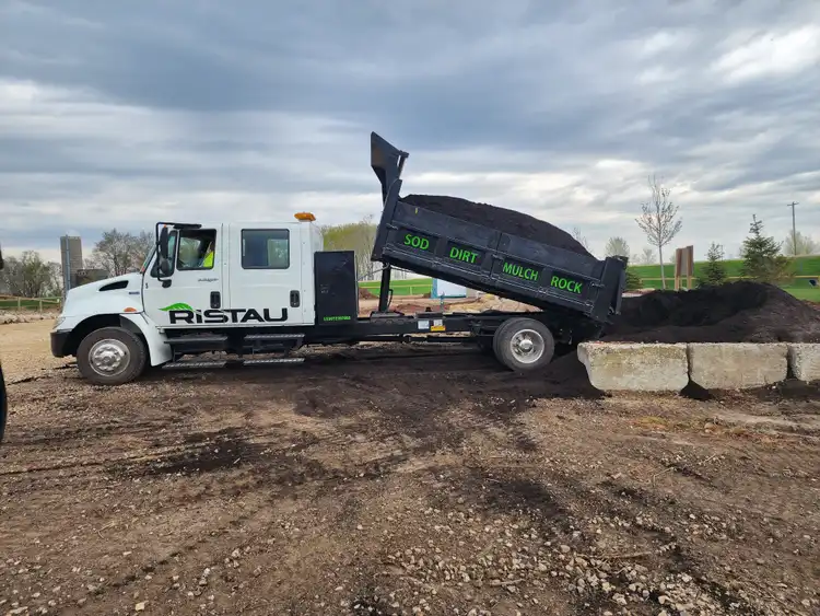 Ristau dump truck unloading topsoil and fill dirt on job site