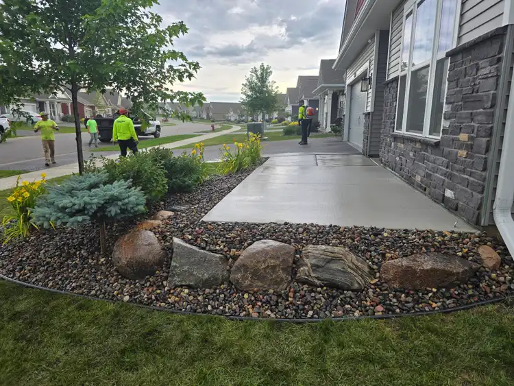 Fresh concrete walkway and patio slab with landscape bed at new construction home