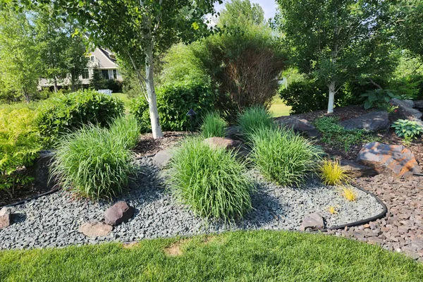 Completed landscape design with ornamental grasses and decorative rock bed