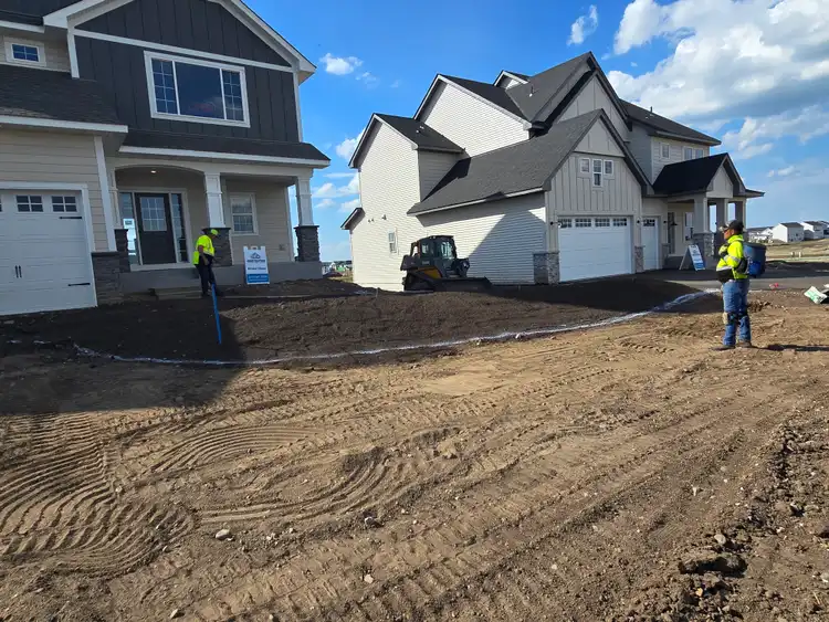 Crew grading soil at new construction residential development for sod installation