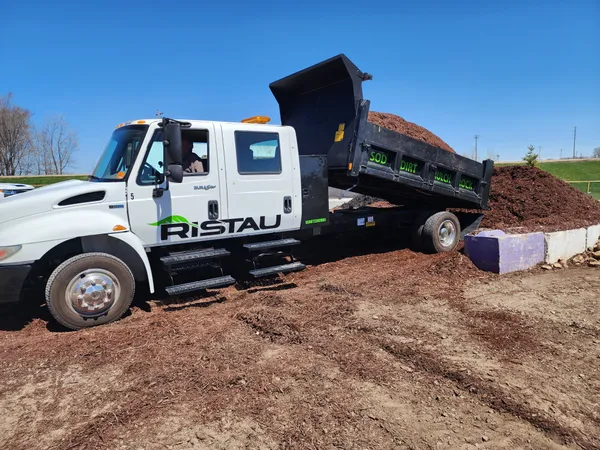 Ristau branded dump truck unloading bulk mulch on delivery