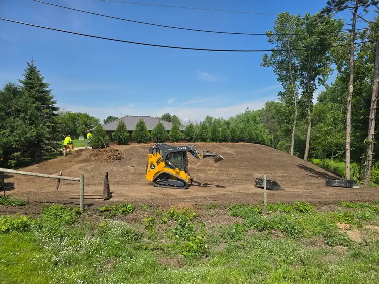 John Deere skid steer grading residential site for sod installation with crew