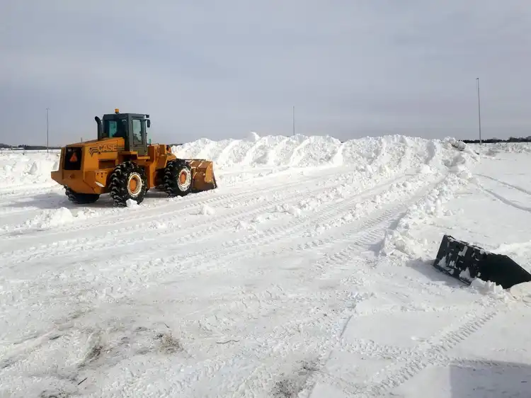 Case wheel loader stacking large snow piles in commercial lot